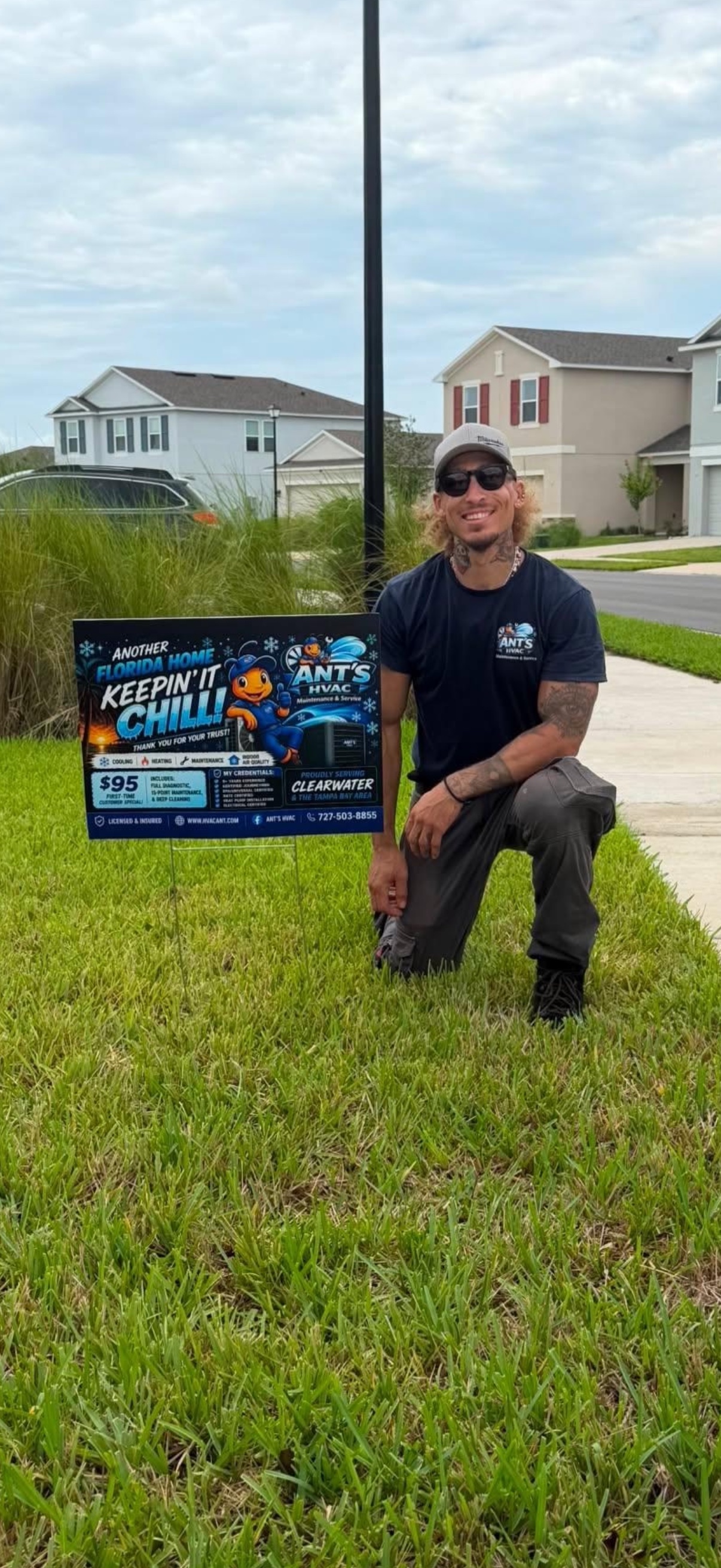 Anthony Stelter, Founder and Lead Technician of Ant's HVAC, kneeling beside an Ant's HVAC yard sign on a customer's lawn in the Clearwater, Florida area